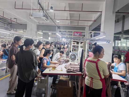 图为驻村队员指导村民参观就业厂区。蓝卫北 摄