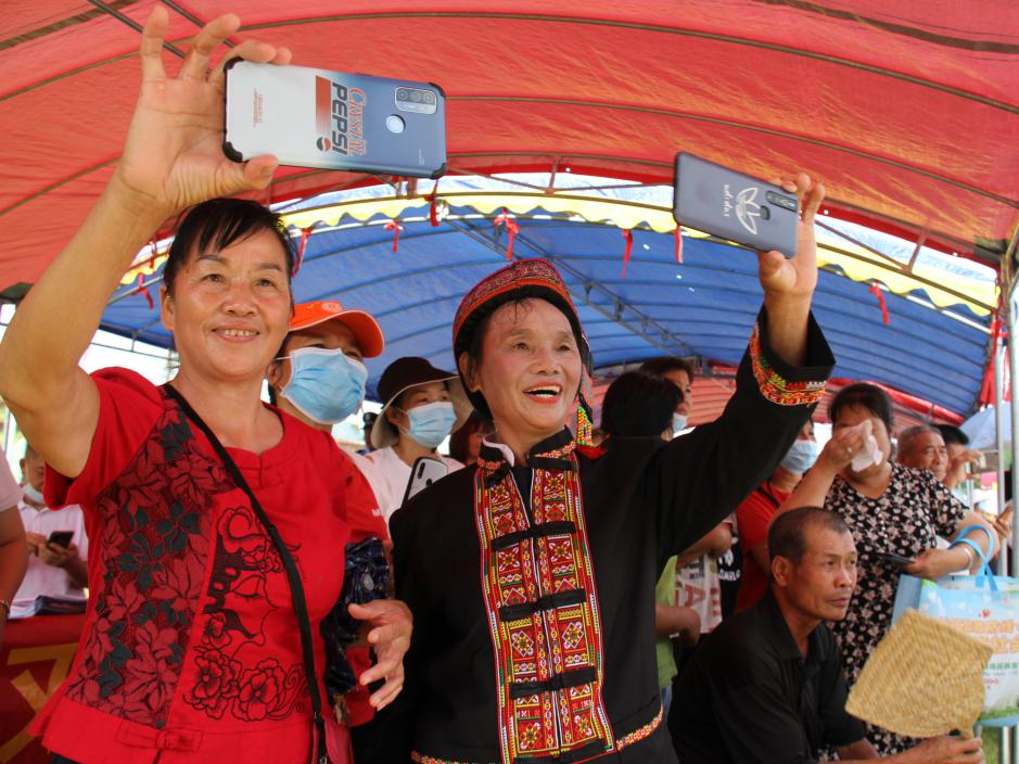 贡模屯丰收节现场村民用手机记录精彩瞬间。覃丽丽 摄.png